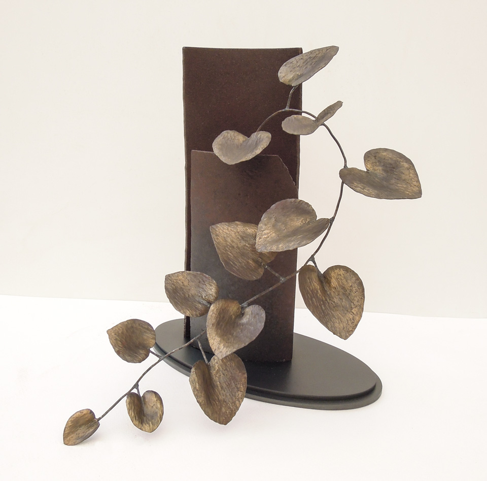 カンガルーアイビーをモチーフにしたアイアンアート作品。 鍛造によって繊細なハンマートーンを施した葉が、元気に伸びている姿です。大小のあるハート型の葉のリズム感が可愛らしい雰囲気です。 ベースも含め全て鉄で、クリア塗装仕上げです。色味の違いは鉄の仕上げで表現しています。