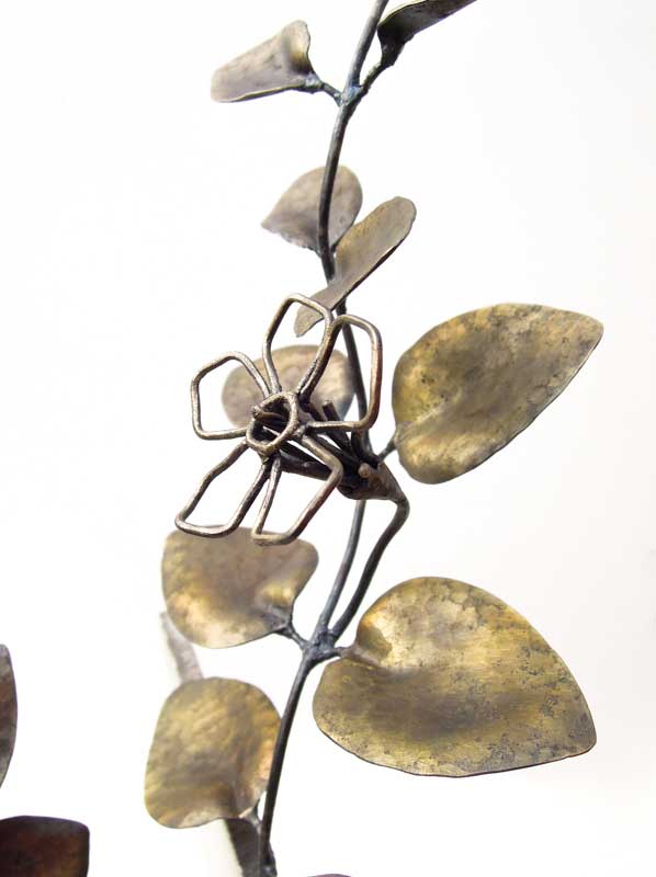 厚みのあるステンレス板の隙間からツルニチニチソウが伸びている様子を鍛鉄で表現したアート作品、花のアップ。花はワイヤーワーク表現で葉はソリッド表現になっています。