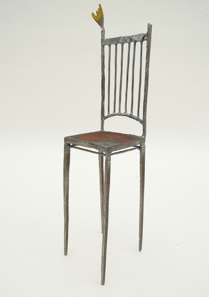 鉄で出来ている椅子のオブジェ。スタイリッシュなハイバックデザイン。卓上サイズながら繊細に作りこまれたディテール。トップに小さな翼が付いています。斜めからの写真。