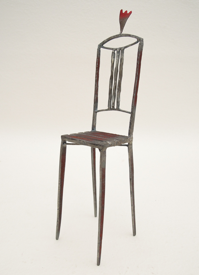 鉄で出来ている椅子のオブジェ。スタイリッシュなハイバックデザイン。卓上サイズながら繊細に作りこまれたディテール。トップに小さな翼が付いています。斜めからの写真。