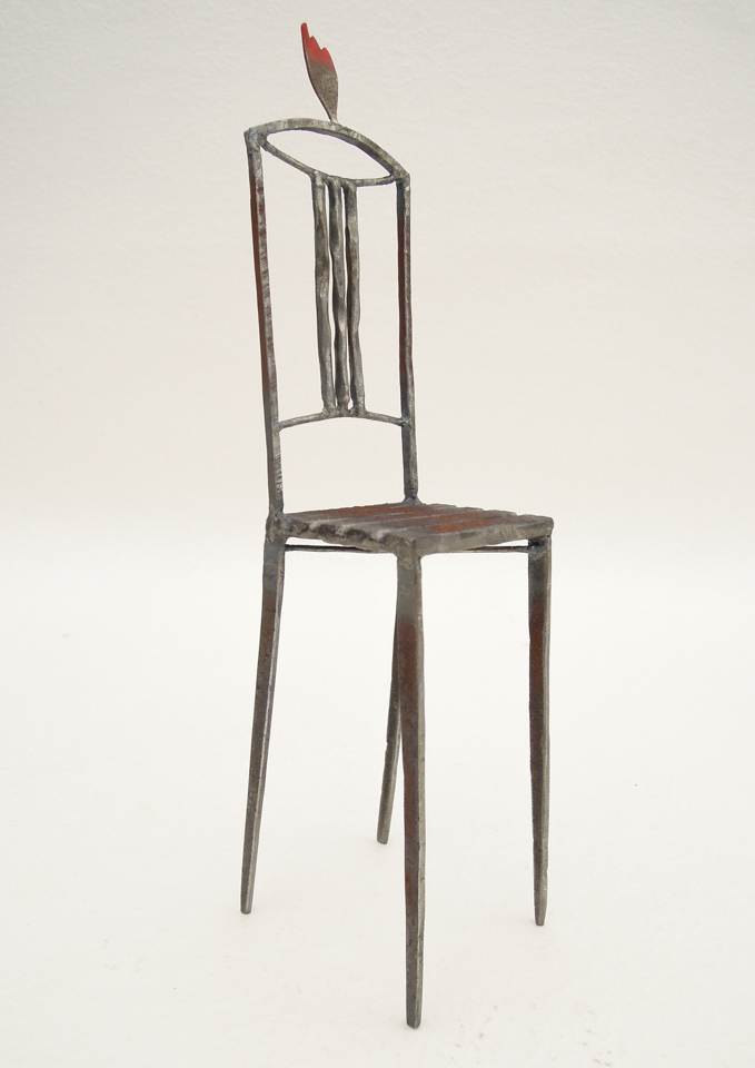 鉄で出来ている椅子のオブジェ。スタイリッシュなハイバックデザイン。卓上サイズながら繊細に作りこまれたディテール。トップに小さな翼が付いています。斜めからの写真。