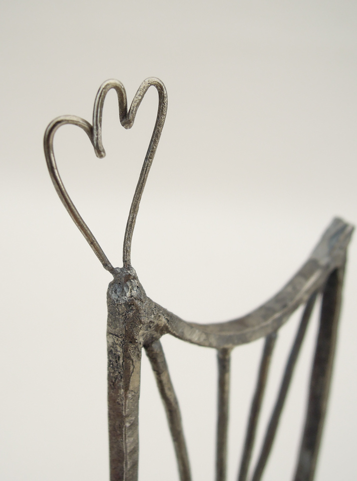 鉄で出来ている椅子のオブジェ。スタイリッシュなハイバックデザイン。卓上サイズながら繊細に作りこまれたディテール。トップ付いた小さな翼のアップ写真。とても細い鉄線を鍛造したもので作っています。