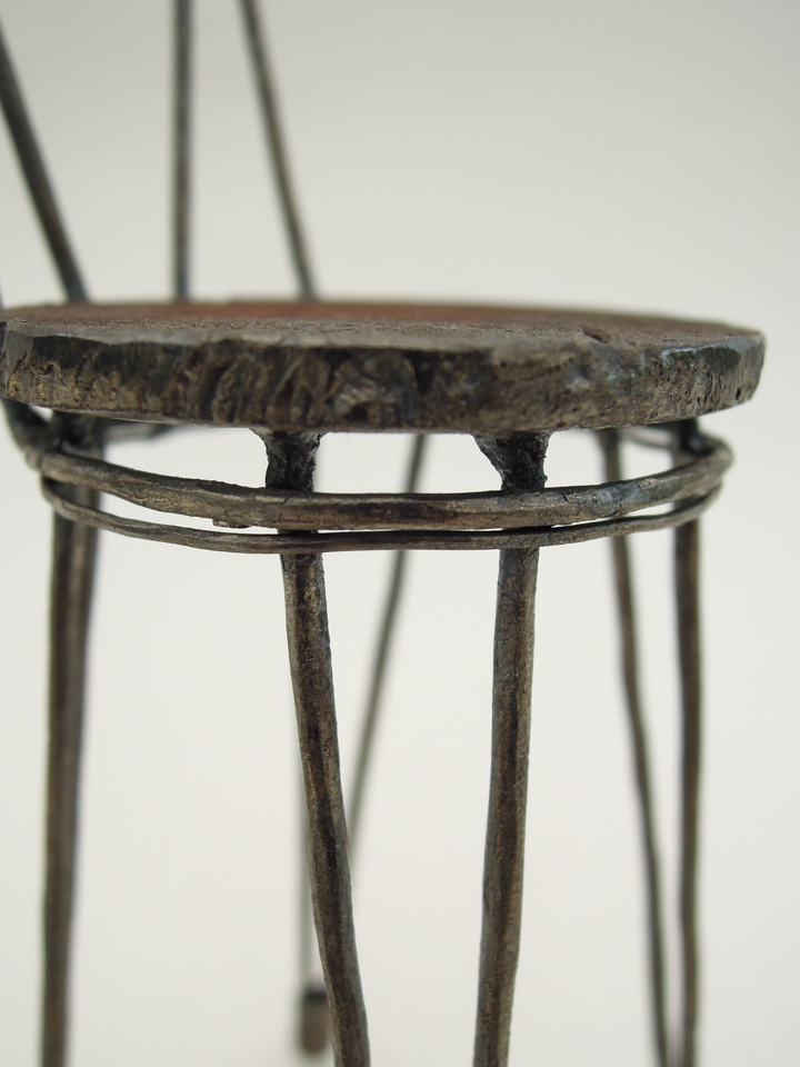 鉄で出来ている椅子のオブジェ。スタイリッシュなハイバックデザイン。卓上サイズながら繊細に作りこまれたディテール。座面と脚の付け根アップ写真。