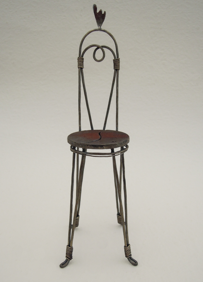 鉄で出来ている椅子のオブジェ。スタイリッシュなハイバックデザイン。卓上サイズながら繊細に作りこまれたディテール。トップに小さな翼が付いています。正面からの写真。