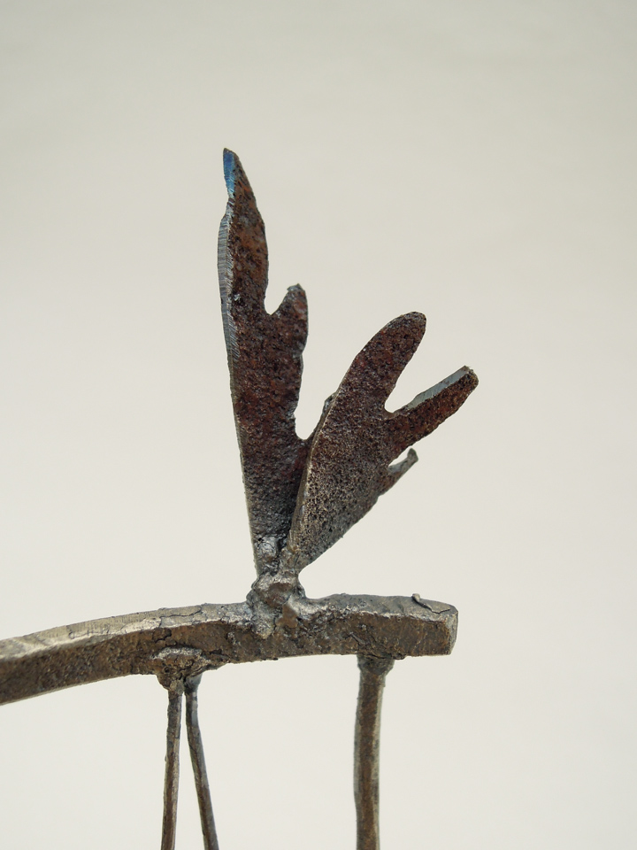 鉄で出来ている椅子のオブジェ。スタイリッシュなハイバックデザイン。卓上サイズながら繊細に作りこまれたディテール。トップ付いた小さな翼のアップ写真。