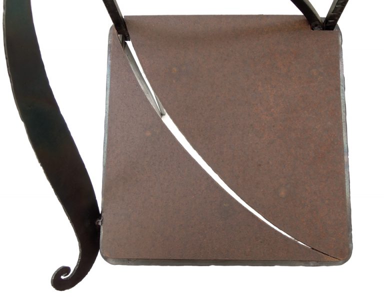 鉄で出来ている実際に座れる椅子のオブジェ。シンプルな背のデザインと、トップの翼と右側に着いた飾りが特徴的です。 座面の写真。スリットが入っています。