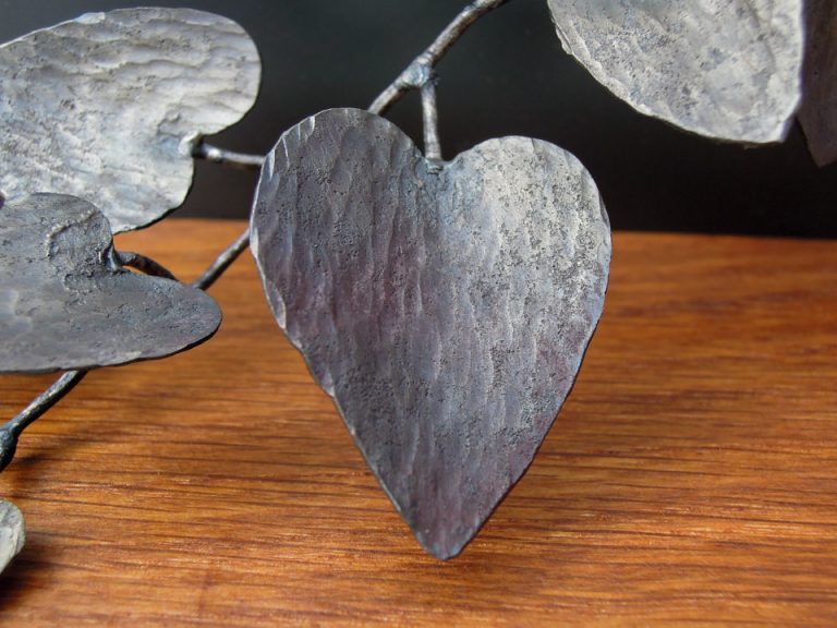 四角い窓から様々な植物が溢れでているようなアートオブジェです。鉄で作られたカンガルーアイビーの葉ののアップ。錆鉄を鍛造したハンマートーンが見えます。部分写真。