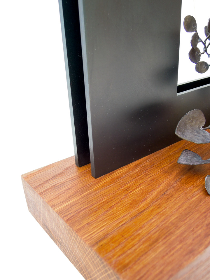 四角い窓から様々な植物が溢れでているようなアートオブジェです。窓の部分の鉄板とベースの木の取り付き、部分写真。