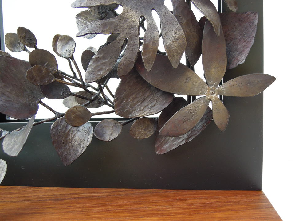 四角い窓から様々な植物が溢れでているようなアートオブジェです。窓と植物は鉄、ベースは木でできています。それぞれの植物は丁寧に作りこまれています。部分写真。