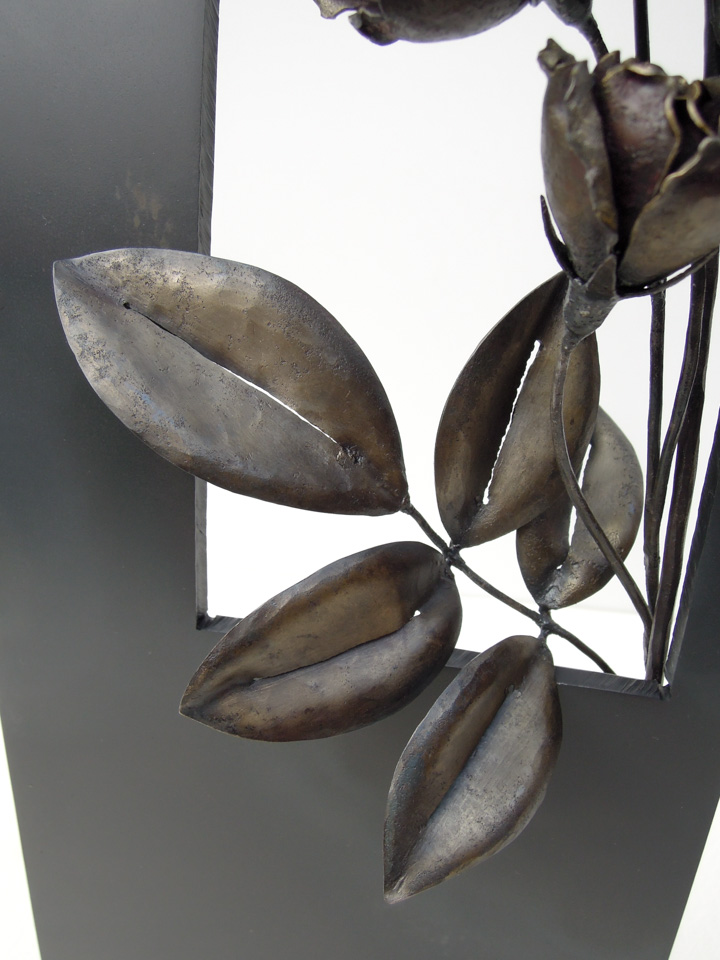 縦長の窓から一枝のバラが咲き誇っている鉄のアートオブジェです。葉の表現アップ写真。