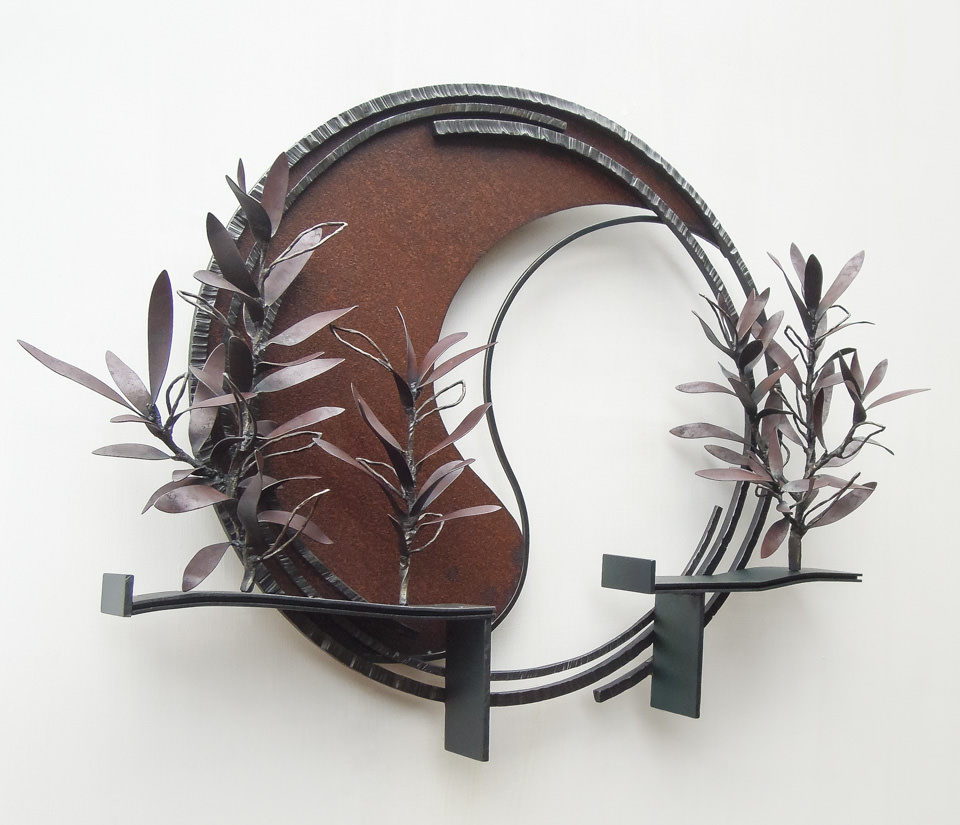 勢いよく伸びるオリーブの枝を鉄で表現した壁面アート作品です。葉は面と線の表現を混在させ、背景に円を切り欠いた面を配置しました。全体写真。