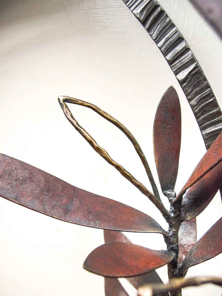 勢いよく伸びるオリーブの枝を鉄で表現した壁面アート作品です。葉は面と線の表現を混在させ、背景に円を切り欠いた面を配置しました。オリーブの部分写真。