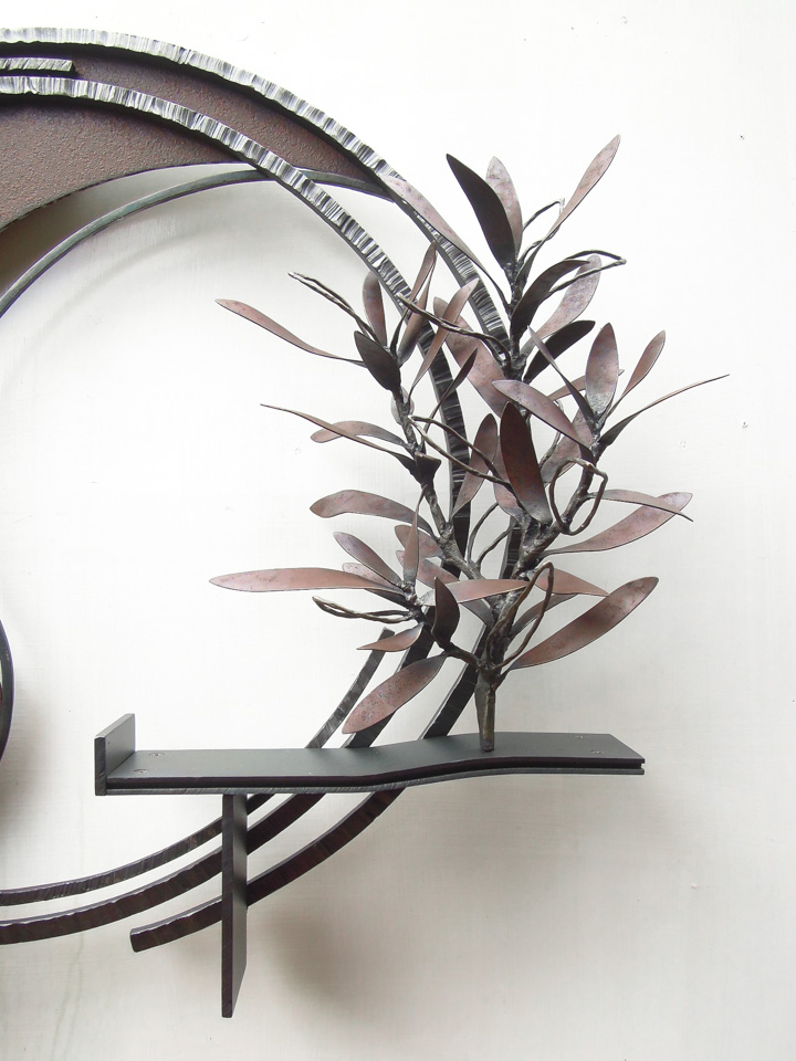 勢いよく伸びるオリーブの枝を鉄で表現した壁面アート作品です。葉は面と線の表現を混在させ、背景に円を切り欠いた面を配置しました。オリーブの部分写真。