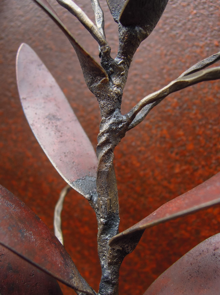 勢いよく伸びるオリーブの枝を鉄で表現した壁面アート作品です。葉は面と線の表現を混在させ、背景に円を切り欠いた面を配置しました。オリーブの部分写真。
