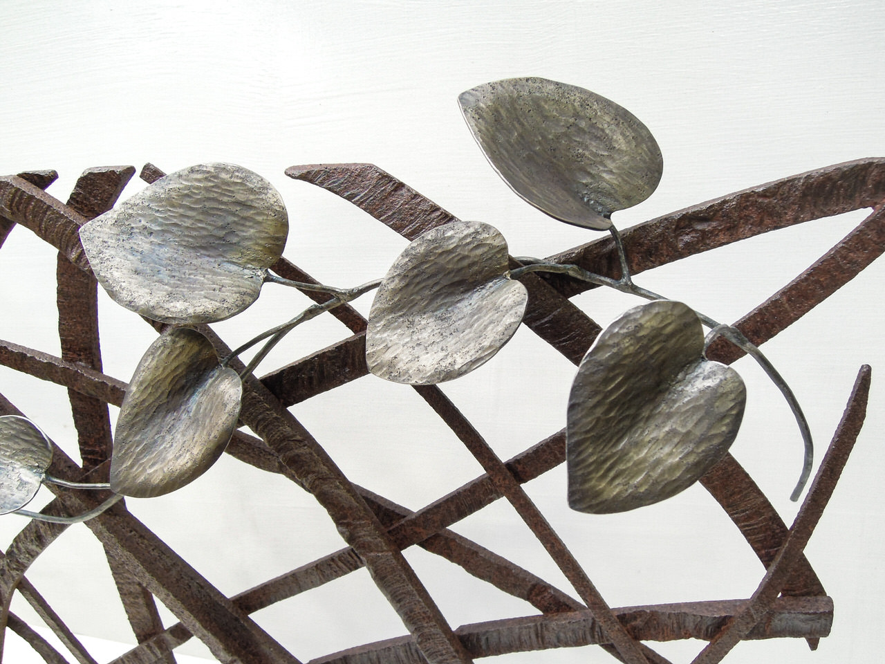 風の流れを模したラインを3枚のプレートで展開し、カンガルーアイビーが寄り添う鍛鉄アートの作品です。葉の写真。