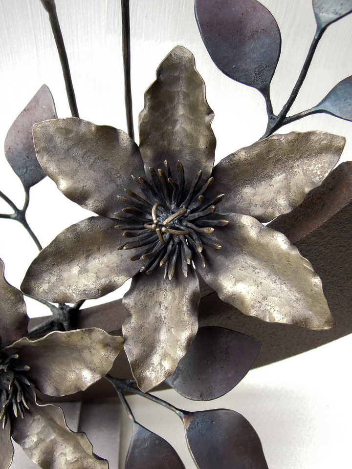 弓状の鉄プレートに鍛鉄のクレマチスの花が添えられたアート作品です。花の詳細。