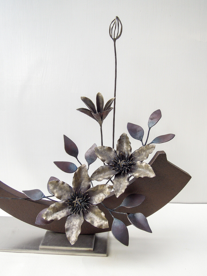 弓状の鉄プレートに鍛鉄のクレマチスの花が添えられたアート作品です。花の部分。