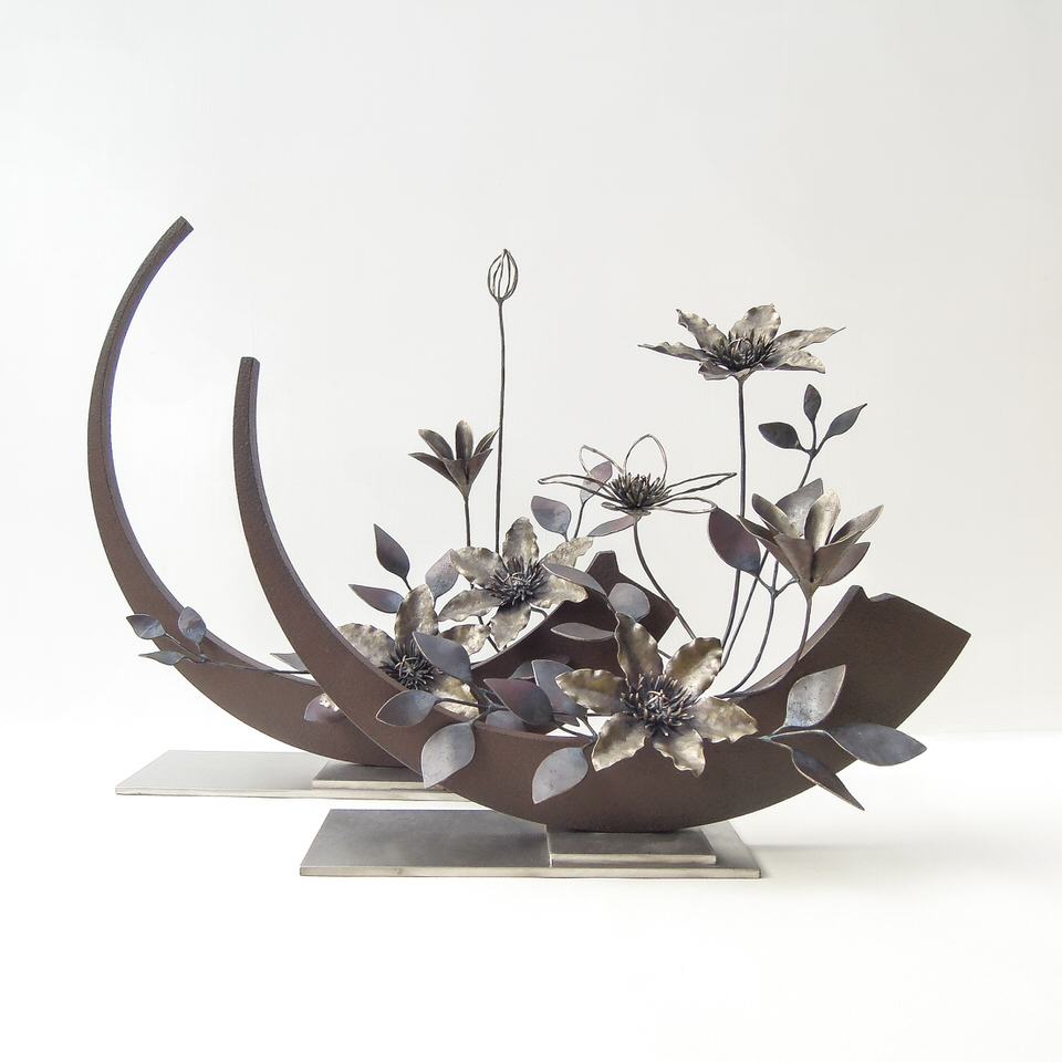 弓状の鉄プレートに鍛鉄のクレマチスの花が添えられたアート作品です。２基を組み合わせた写真。
