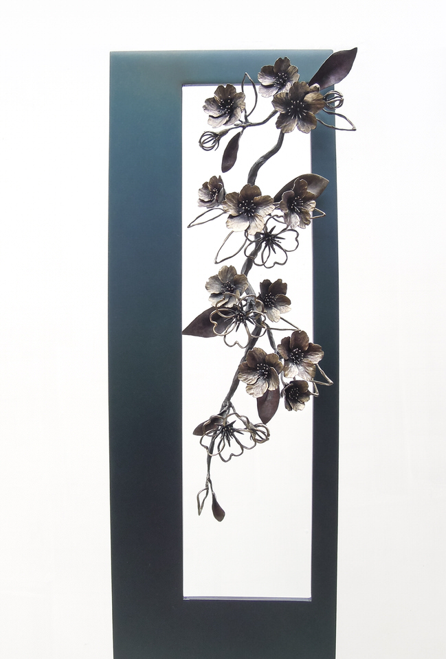 青みを残して黒焼きした鉄のプレートの窓から、鍛鉄の桜の枝が下がっている姿のアート作品です。枝ぶり。