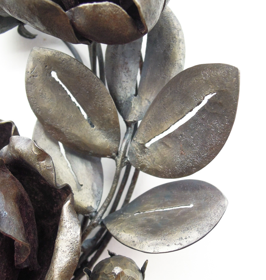 バラの花を溢れるように配置した鍛鉄のリースです。添えられた葉の表現。