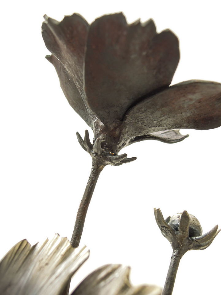 円の鉄プレートに鍛鉄のコスモスの花が添えられた彫刻作品です。コスモスの萼の表現。